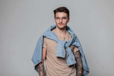 Fashionable handsome hipster guy with hair and tattoos on his arms wearing stylish casual clothes...