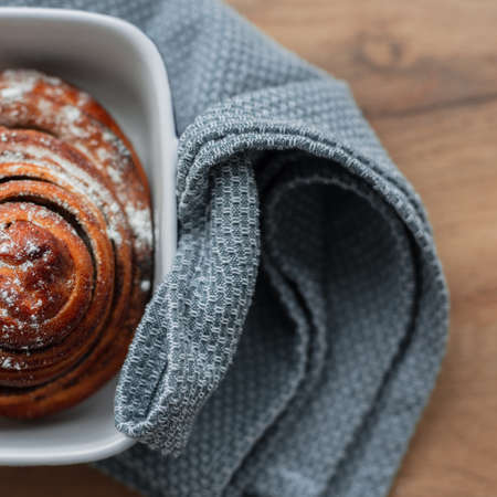 Delicious bun with poppy seed and powdered sugar on a napkin, top view. Freshly baked, cinnabonの写真素材