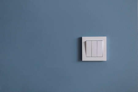 White light switch on blue wall. Free space for design and text. Creative idea - turn onの写真素材