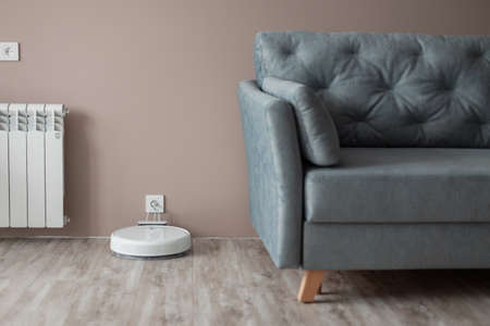 Modern beautiful interior with a sofa and a smart robot vacuum cleaner