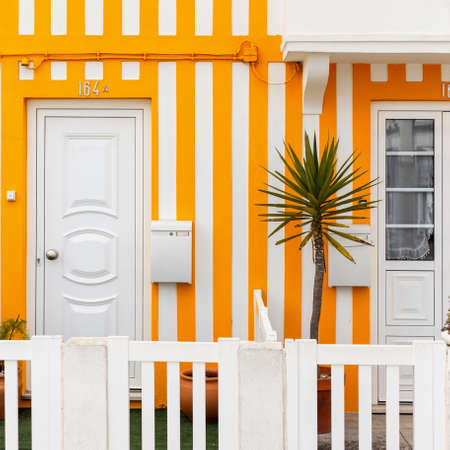 Vintage beautiful striped yellow house with doors, white mailbox and palm tree on the terrace