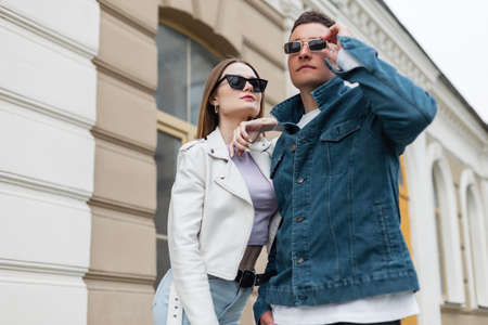 Cool fashionable young beautiful couple girl and boy with sunglasses in fashion casual outfit with denim jacket and leather jacket walks in the city. trendy stylish clothes looksの写真素材