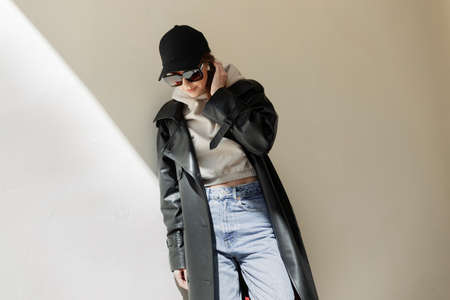 Cool fashion street beautiful woman hipster with trendy sunglasses and black cap in casual urban...