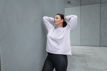 Stylish beautiful fashionable young woman in sportswear with a purple trendy sweatshirt with black...
