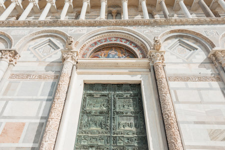 Beautiful Romanesque cathedral architecture building with columns and a beautiful green door in Pisa, Italyの写真素材