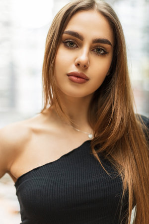 Female stylish portrait of a beautiful young woman with green eyes and nature fresh beauty face in a fashion black one-shoulder topの写真素材