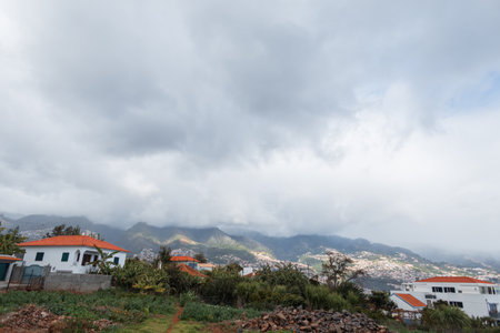 Beautiful mountain landscapes with houses on a cloudy day with clouds. Madeira island and hillsの写真素材