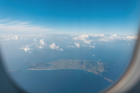 Air plane flies over the island of Porto Santo, view from the porthole. plane travel. Airplane in the sky over the oceanの写真素材