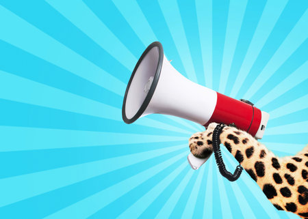 Leopard holds a loudspeaker in paw on a vintage light blue background. Business and management, creative idea. Shouts and attention, concept.の写真素材