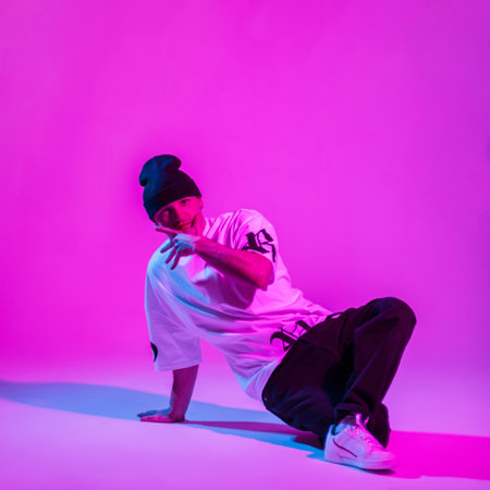 Stylish trendy professional dancer b-boy guy in fashion clothes dancing in a creative studio with...