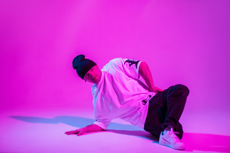 Professional breakdance man in fashion clothes dances in creative studio with pink and neon lightの写真素材