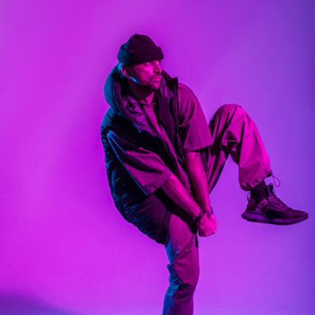 Fashionable young professional dancer man in fashion clothes dancing in colorful studio with creative pink and neon lightの写真素材