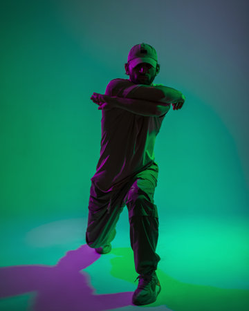 Fashionable handsome professional man dancer with cap in fashion clothes dancing in creative studio...