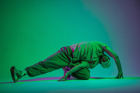 Professional dancer fashionable man with a cap in stylish clothes dancing in a creative studio with cyan and magenta lightsの写真素材