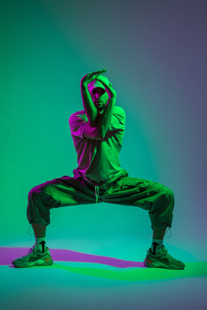 Fashionable handsome stylish dancer man in trendy fashion clothes with sneakers dancing in a colorful studioの写真素材