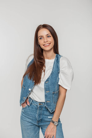 Cheerful beautiful young stylish girl with a smile in fashion denim clothes on a white background in the studioの写真素材