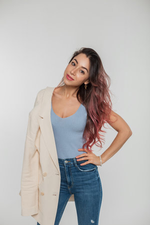 Fashionable beautiful young woman model with pink hair in stylish casual outfit with a blazer on her shoulder posing in the studio on a white backgroundの写真素材