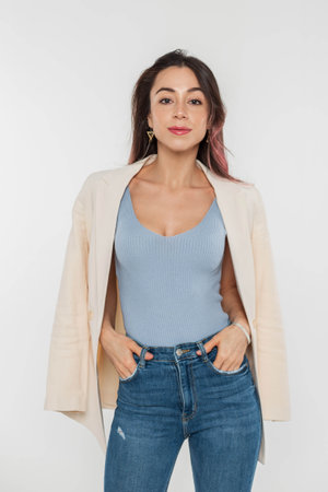 Pretty fashionable young woman with pink hair in blue trendy top and jeans with blazer on a white backgroundの写真素材