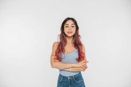 Beautiful young woman with freckles and pink hair in a fashion blue top and jeans stands on a white...