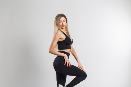 Beautiful athletic fitness woman blonde in fashionable black sportswear posing on a white backgroundの写真素材
