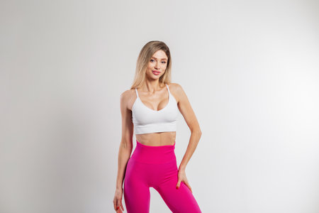 Fashion beautiful sports fit girl with a smile in fashionable sportswear with a top and pink leggings on a white backgroundの写真素材