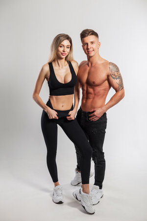 Beautiful sporty fit couple in the studio. Beautiful girl with a slim body in fashionable sportswear and a handsome athletic muscular man on a white backgroundの写真素材