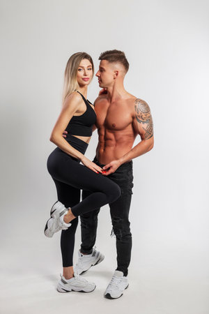 Slender beautiful fit couple on a white background in the studio. Handsome athletic muscular man and beautiful fitness blond girl in sportswear with sneakersの写真素材