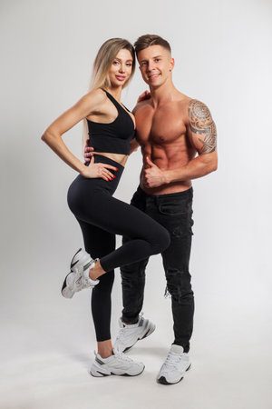 beautiful athletic slim girl and a handsome strong muscular man in fashion sportswear poses together on a white background. Sport family and healthyの写真素材