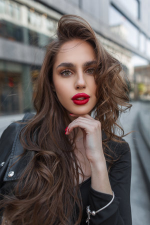 Amazing beauty street portrait of a beautiful fashionable chic woman with red lips in trendy fashion clothes in the city. Pretty ladyの写真素材