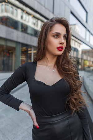 Pretty chic lady with red lips in black fashion elegant clothes walks in the cityの写真素材
