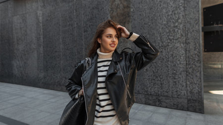 Cool fashion hipster beautiful woman model with smile in urban fashionable clothes with sweater,...