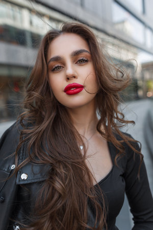 Cool fashion beauty chic lady with red lips in casual outfit with leather jacket walks outdoor in the cityの写真素材