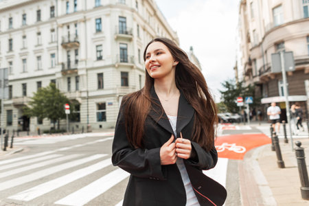 Fashion happy pretty young woman with smile in casual street outfit with white blazer and white dress walks in the cityの写真素材