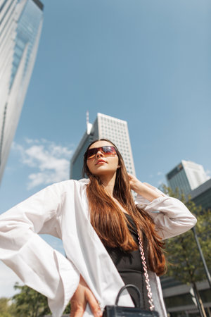 beautiful young fashion slender woman in fashionable clothes with sunglasses walks in the city on a sunny dayの写真素材