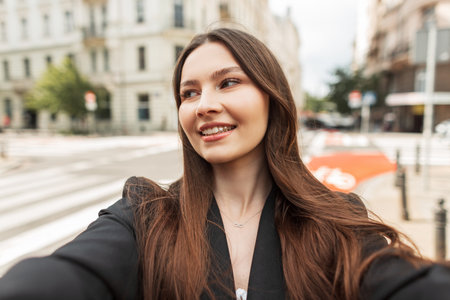 Happy beautiful fresh young girl model with smile in trendy fashion clothes taking selfie photo and walking in the cityの写真素材