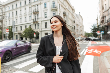 Fashionable young street happy woman with smile in casual outfit in black blazer walks in the cityの写真素材