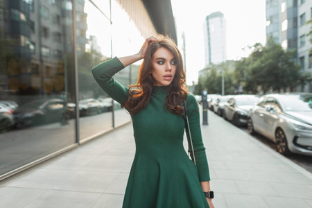 Gorgeous beautiful fashionable brunette chic. woman in fashion trendy outfit with a green dress walks in the cityの写真素材