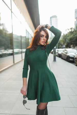Elegant glamorous young stylish lady in a trendy fashion green dress with sunglasses walks in the cityの写真素材