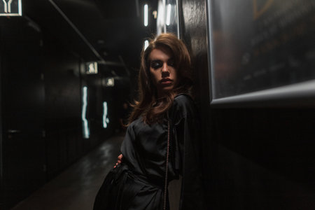 Beautiful young fashionable lady in a trendy fashion black dress in the darkの写真素材