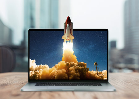 Space rocket shuttle with a cloud of smoke and blast takes off from a laptop on a working office desk. creative idea and startup. successful business project. go outside the frameの写真素材
