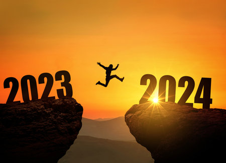 Man jumping on cliff 2024 over the precipice at amazing sunset. New Year's concept. Symbol of starting and welcome happy new year 2024. People enters the year 2024, creative ideaの写真素材