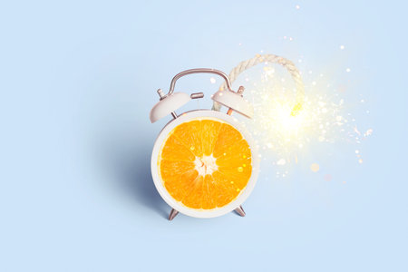Creative vintage alarm clock orange bomb with wick and sparks on a blue background, concept. Advertising and marketing, creative idea. Vitamin Cの写真素材