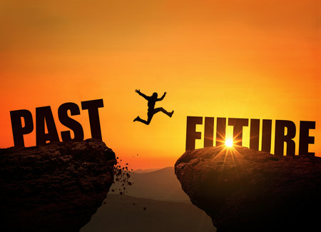 Successful man jumps over a cliff with the text Future at sunset, concept. Leap from past to future, creative idea. Rock at sunriseの写真素材
