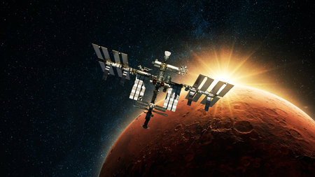 ISS spacecraft flies against the backdrop of dawn light and red planet Mars with craters in deep space. Journey to Mars, conceptの写真素材