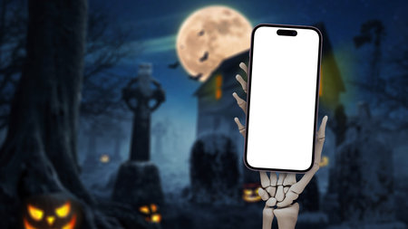 Dead man Skeleton hand holding mockup smartphone on cemetery with full moon, pumpkins, bats and dark house at night, creative Halloween idea. Halloween app message and advertisement, conceptの写真素材
