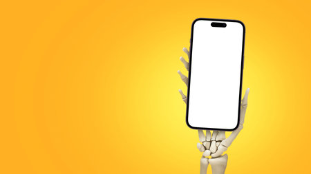 Skeleton hand holding smartphone on orange background, Halloween concept. Advertising and smartphone, creative idea. Phone mock up halloween.の写真素材
