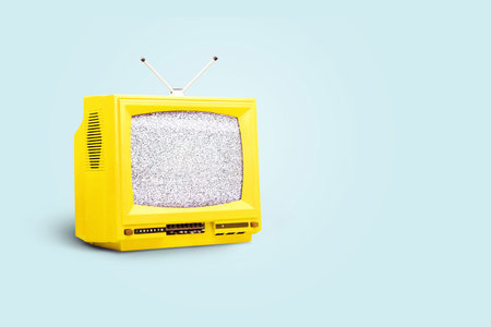 Yellow vintage TV with a white noise on a blue background. Creative idea, propaganda and mediaの写真素材