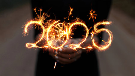 Girl holds a sparkler in her hands and draws 2025 with sparks. New Year 2025, creative idea.