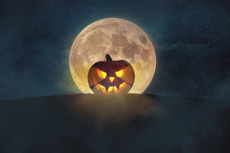 Halloween pumpkin with lights on a hill with a full moon and stars in the fog. Scary Halloween Wallpaper. Creative Halloween Party Ideas At Nightの素材