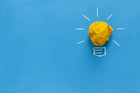Inspiration concept crumpled paper light bulb metaphor for good idea. Yellow crumpled paper light...